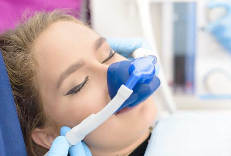 A woman receiving oxygen therapy with a nasal mask in a clinical setting.